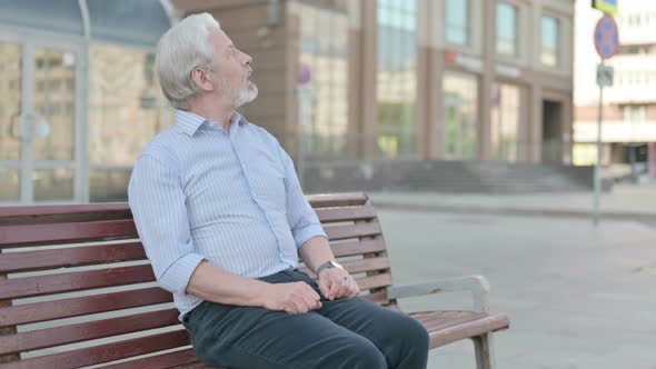 Waiting Old Man Checking Time on Watch While Sitting Outdoor on Bench