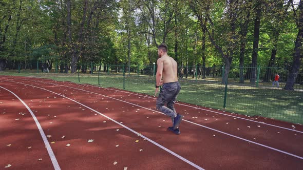 Sport man running on racetrack, View of athletic shirtless sportsman running on track