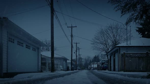 Snow Falls On Road Between Houses In The Evening