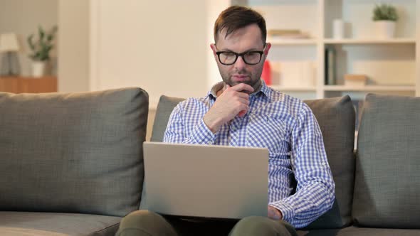 Pensive Young Man Using Laptop at Home 