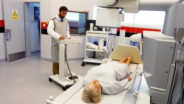 Male doctor sets up the machine to x-ray a female patient