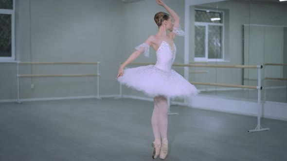 Wide Shot Graceful Ballerina in White Tutu Spinning on Tiptoes in Dance Studio Indoors