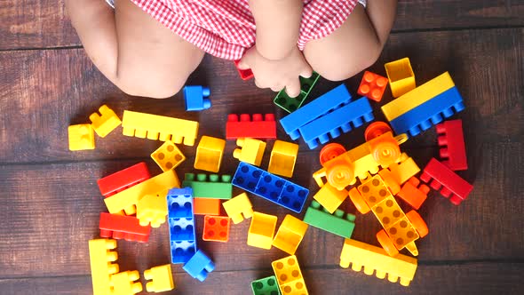 Child Girl Paying with Colorful Building Blocks on Wooden Table , Top View 