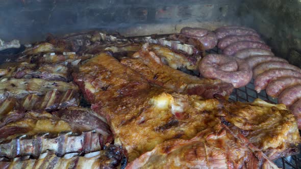 Chorizos, beef and chicken meat roasting on in an Argentinian Asado. WIDE SHOT