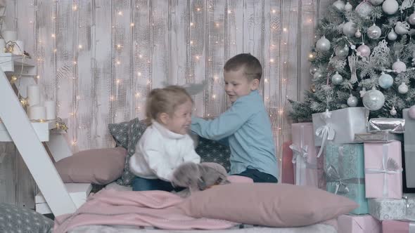 Little Boy and Girl in Sweaters Play with Toys on Cozy Sofa