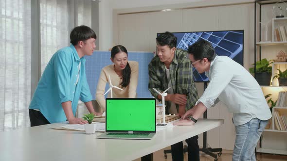 Green Screen Laptop On The Table While Asian Engineers Group Discussing House Model With Solar Panel