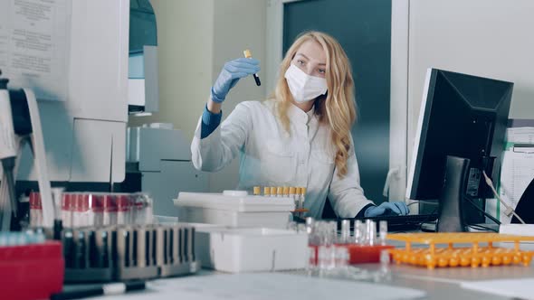 A Microbiology Scientist Checks Test Tubes in the Laboratory and Enters Information Into a Database