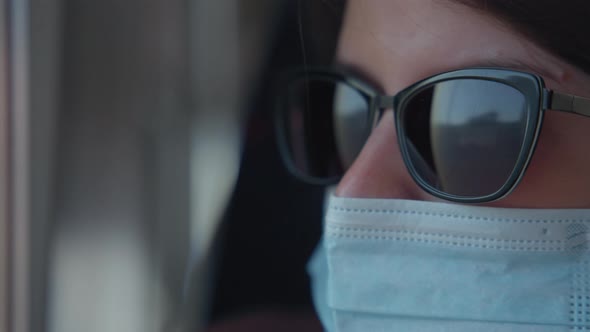 Woman in mask and sunglasses on train