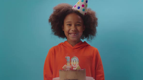 African American girl in birthday hat blowing out number 10 candle in slow motion