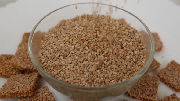 Micro shot of dropping sesame seeds in a glass bowl isolated over white background