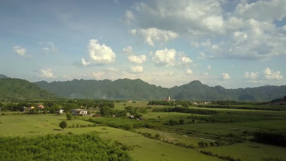 Green Fields at Town Against Mountains Under Sky Aerial View