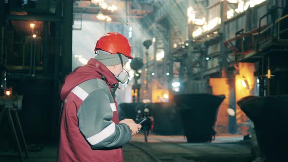 Steel Worker with a Mobile Phone in the Metallurgical Plant