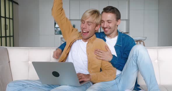 Overjoyed Male Gay Couple Looking at Laptop Screen Rejoices Online Betting Win Lottery Victory