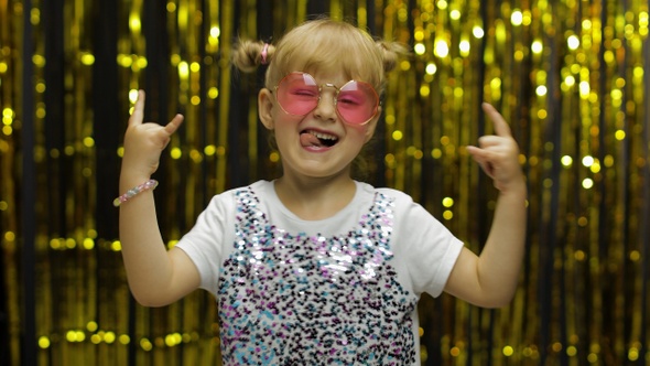 Child Dancing Waving Hands Fooling Around. Girl 4-5 Years Old Posing on Background with Foil Curtain