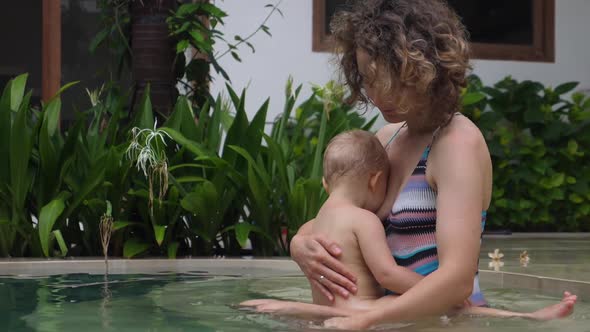 Caucasian Mother Breastfeeds Her Baby in Private Swimming Pool