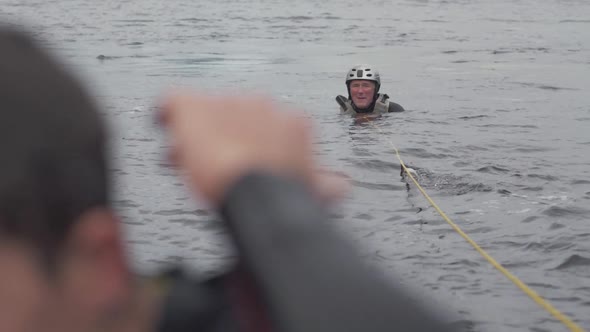 Water skier sits in water beside buoy slalom course