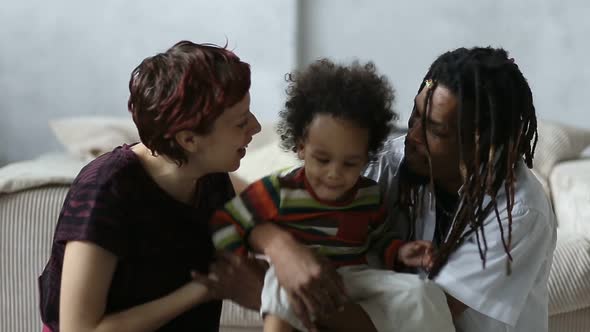 Affectionate Mixed Race Parents Kissing Little Son