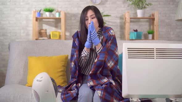 Freezing Young Asian Woman Sitting with Heaters in the Living Room