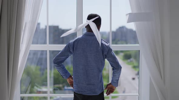 Back View of Stressed African American Man Throwing Out Paperwork Sighing Looking Out the Window in