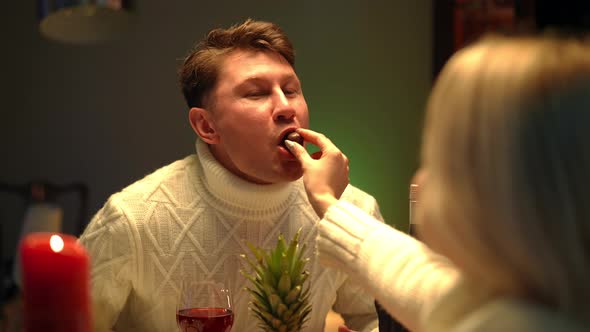 Portrait of Smiling Man Enjoying Tasty Candy As Blurred Woman Feeding Partner