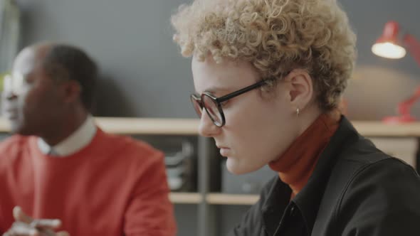 Woman with Prosthetic Arm Working on Laptop during Office Meeting