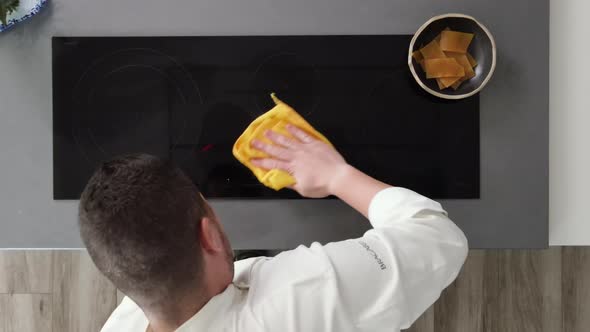 Directly Above View of a Male Chef Cleaning Ceramic Hob in Kitchen Indoors at Home