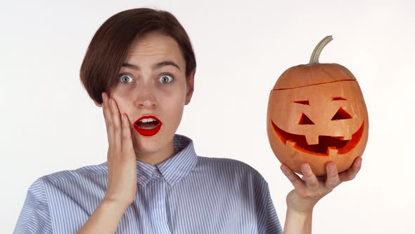 Young Woman Looking Shocked, Posing with Halloween Carved Pumpkin