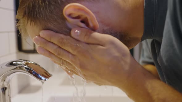 Bearded Hipster Washes Face with Water in Public Toilet