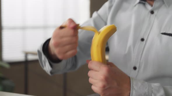 Busy Casual Young Businessman Eating Banana at Office Desk