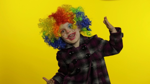 Little Child Girl Clown in Colorful Wig Making Silly Faces, Fool Around, Smiling, Dancing, Halloween