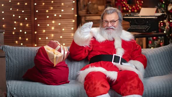 Santa Claus in Festive Costume Waving Hand at Christmas Eve