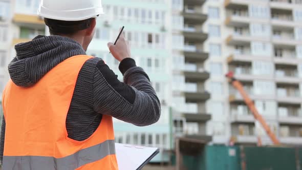 The foreman at the construction site of a high-rise building will check the drawings.