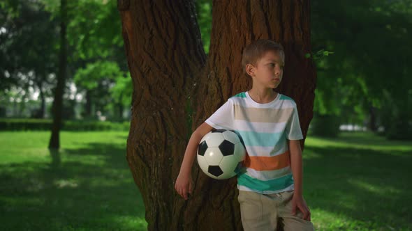 Little Boy Hold Soccerball Lean on Tree