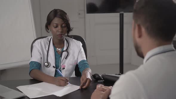 Doctor In White Coat Examining Male Patient In Office, Blood Pressure, African American Black Nurse