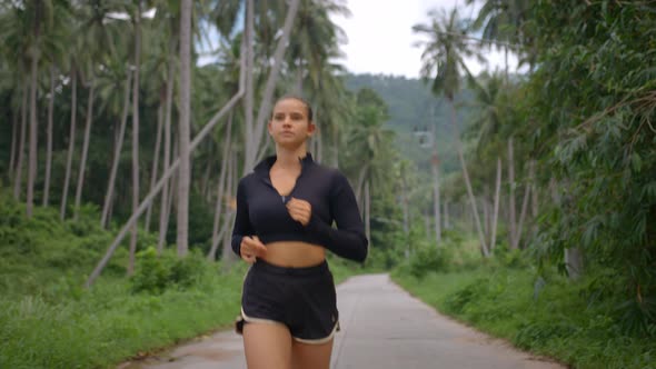 Sporty Girl in Black Shorts and Shirt Jogging Among Tropical Palms Having Excellent Workout Outside