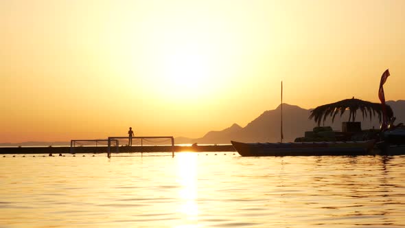 Silhouettes of Children Playing Water Polo in the Sea on the Background of Evening Sky