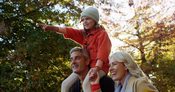 Girl on dads back with mom walking outdoors