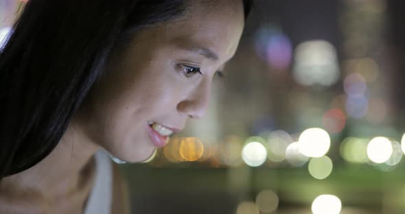 Woman using mobile phone in Hong Kong city at night 