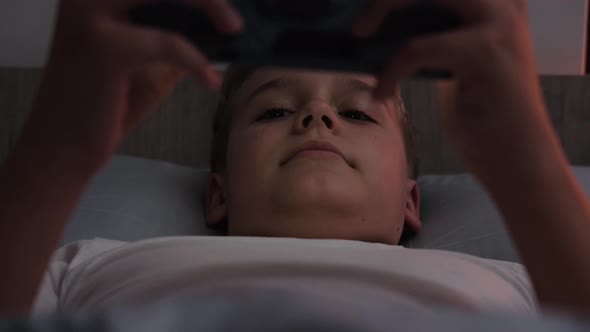 A Teenage Boy Plays Mobile Games While Lying in Bed Before Going to Bed