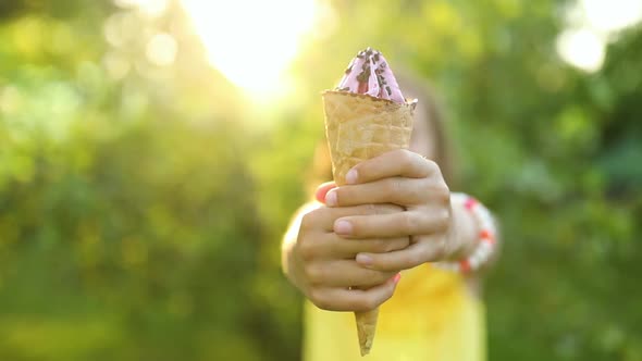 Cute girl eating italian ice cream cone smiling while resting in park on summer day