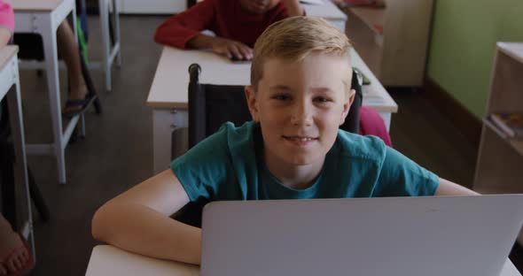 Physically challenged boy using laptop in the class