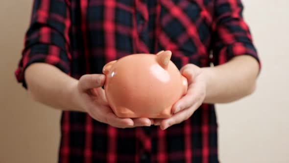 Woman Extends Slim Arms Holding Small Round Piggy Bank