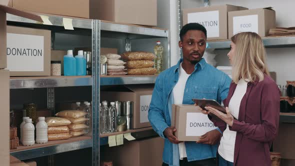 Man and Woman Using Tablet for Inspecting Food Bank Storage