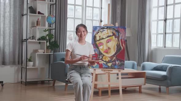 Asian Artist Girl Holding Paintbrush And Smiling After Finish Painting A Girl On The Canvas