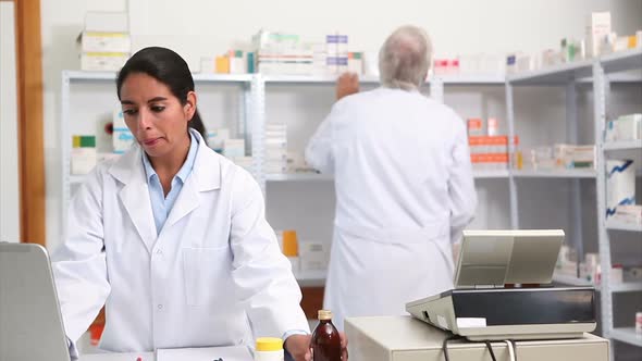 Female pharmacist holding a drug box while smiling