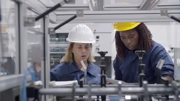 Diverse Female Factory Engineers Using Paper Manual