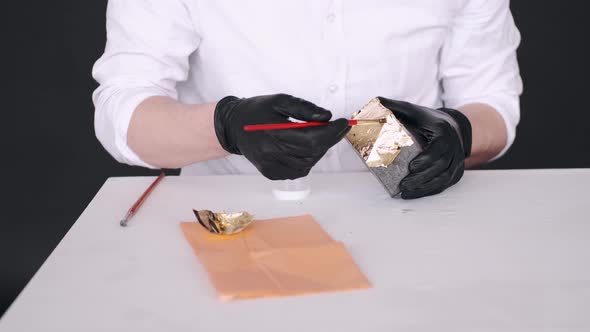 Closeup of Hands in Gloves Holding Brush and Coloring Pot