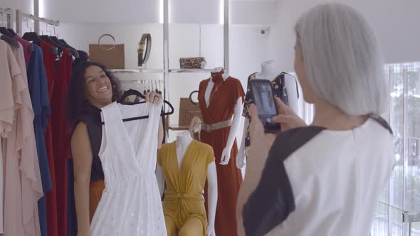 Joyful Latin Woman Choosing Clothes in Fashion Store