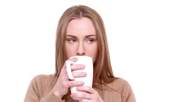 Pensive Young Beautiful Caucasian Female with Light Brown Hair Drinking Hot Tea From Cup Standing on