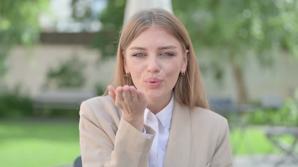 Outdoor Portrait of Young Businesswoman Giving Flying Kiss